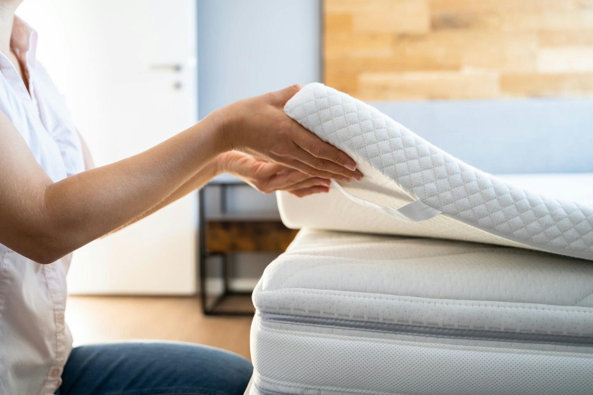 Woman attaching a memory foam mattress topper to a mattress.